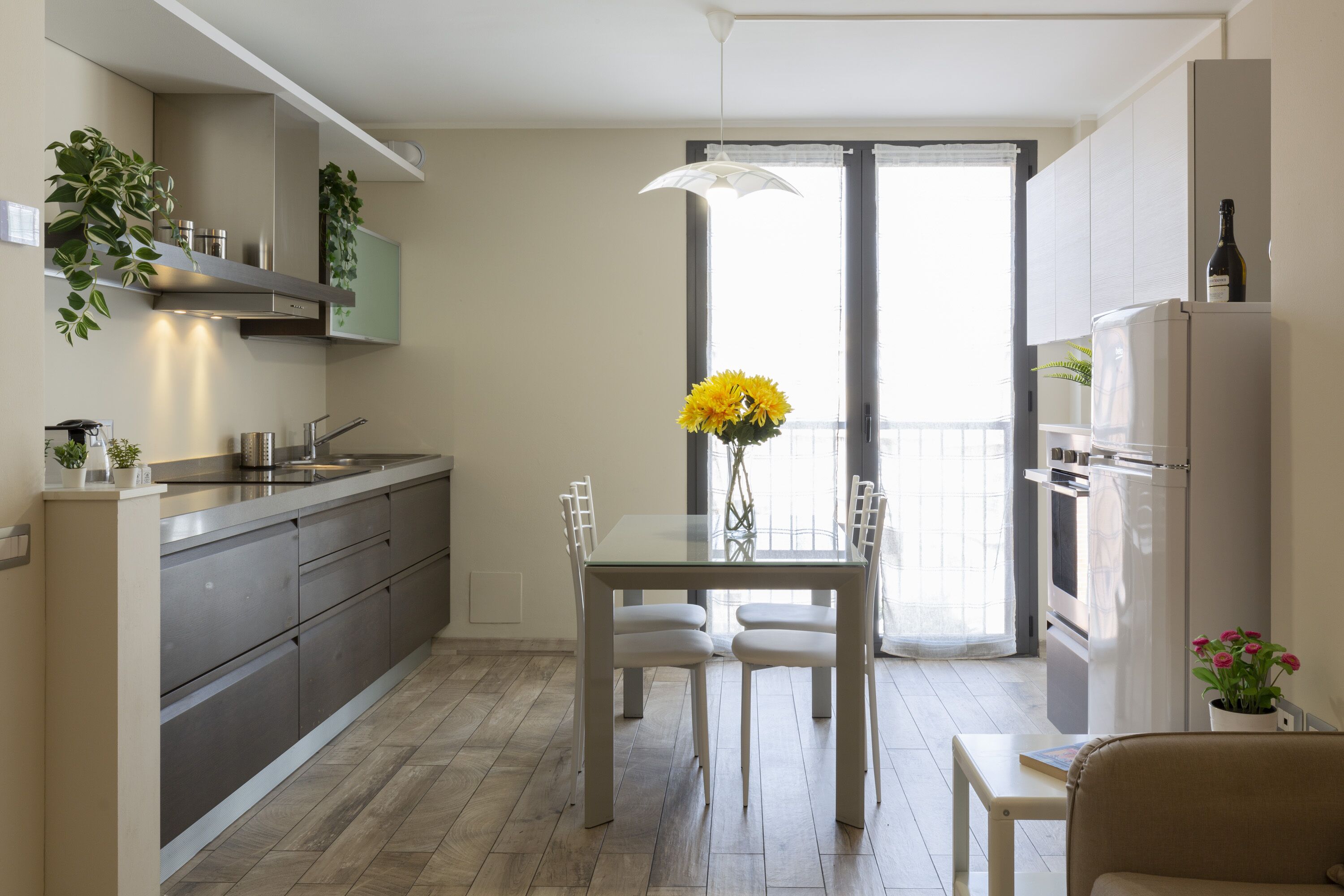 A modern kitchen with a dining table, chairs, and a vase of flowers.