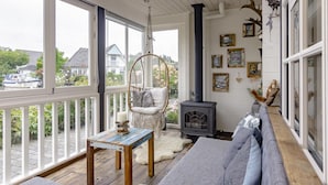 A cozy room with a sofa, a hanging chair, a table, and a fireplace.