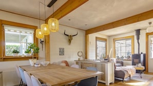 A cozy dining area with a wooden table and chairs, a kitchen area with a stove, and a living space with a sofa and a fireplace.