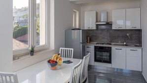 Eine moderne Küche mit weißen Schränken, einem Edelstahl-Kühlschrank und einem Gasherd.