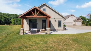 A two-story house with a covered porch, a garage, and a well-maintained lawn. - The Cottage at Heritage Hill (Sugarcreek)