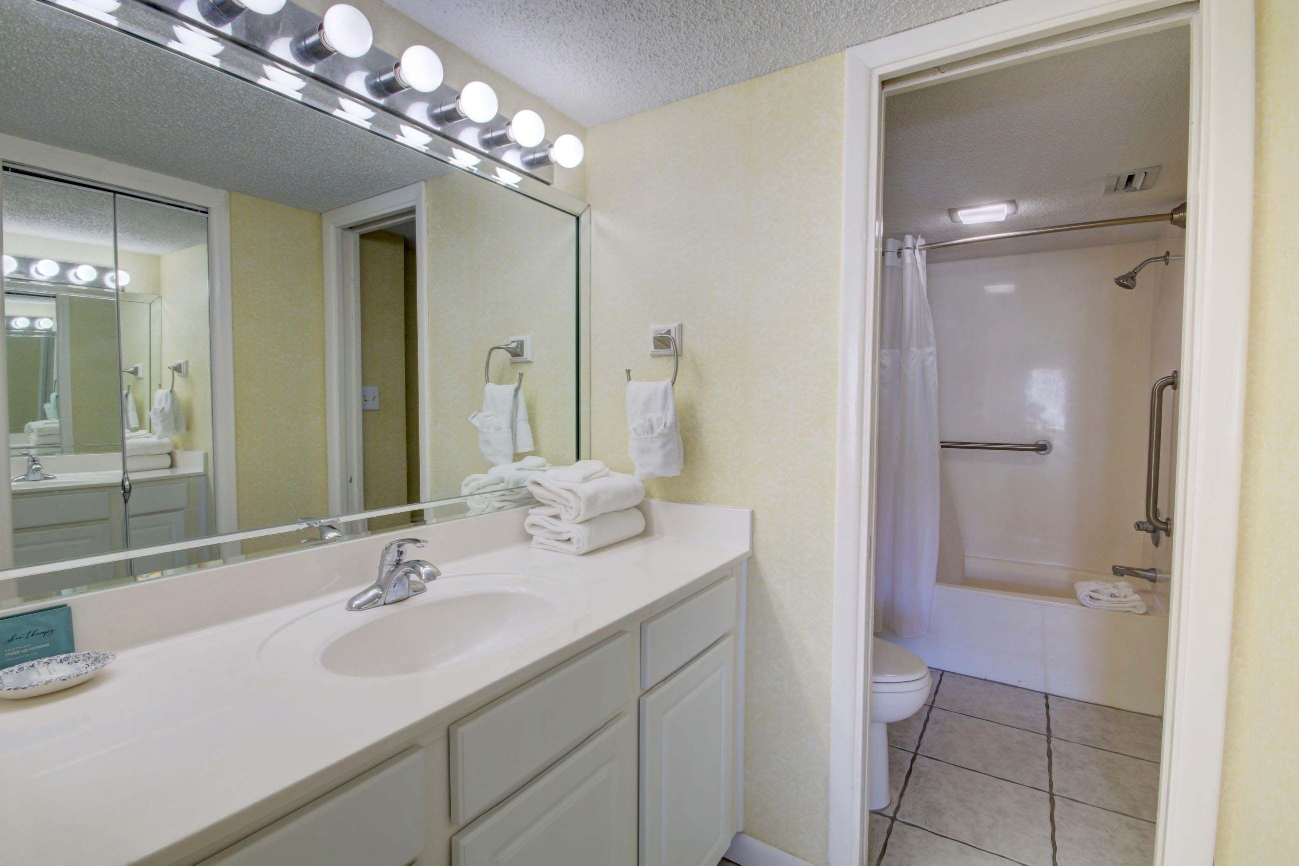 A bathroom with a sink, mirror, and shower.