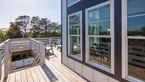 Un bâtiment moderne doté de grandes fenêtres et d’une terrasse en bois.