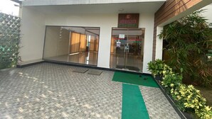 Um edifício moderno com entrada de vidro, uma varanda com guarda-corpo estampado e um tapete verde na frente.