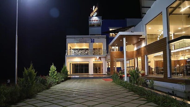 Um hotel com entrada bem iluminada, varanda com grades e placa indicando 'Cafeteria'.