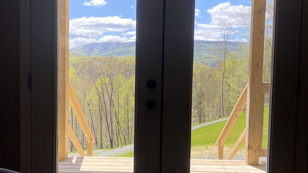 Un juego de puertas dobles con vistas a una terraza de madera y un paisaje montañoso.