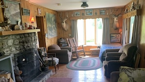 Ein gemütliches Wohnzimmer mit Kamin, Holzwänden und verschiedenen Sitzgelegenheiten.