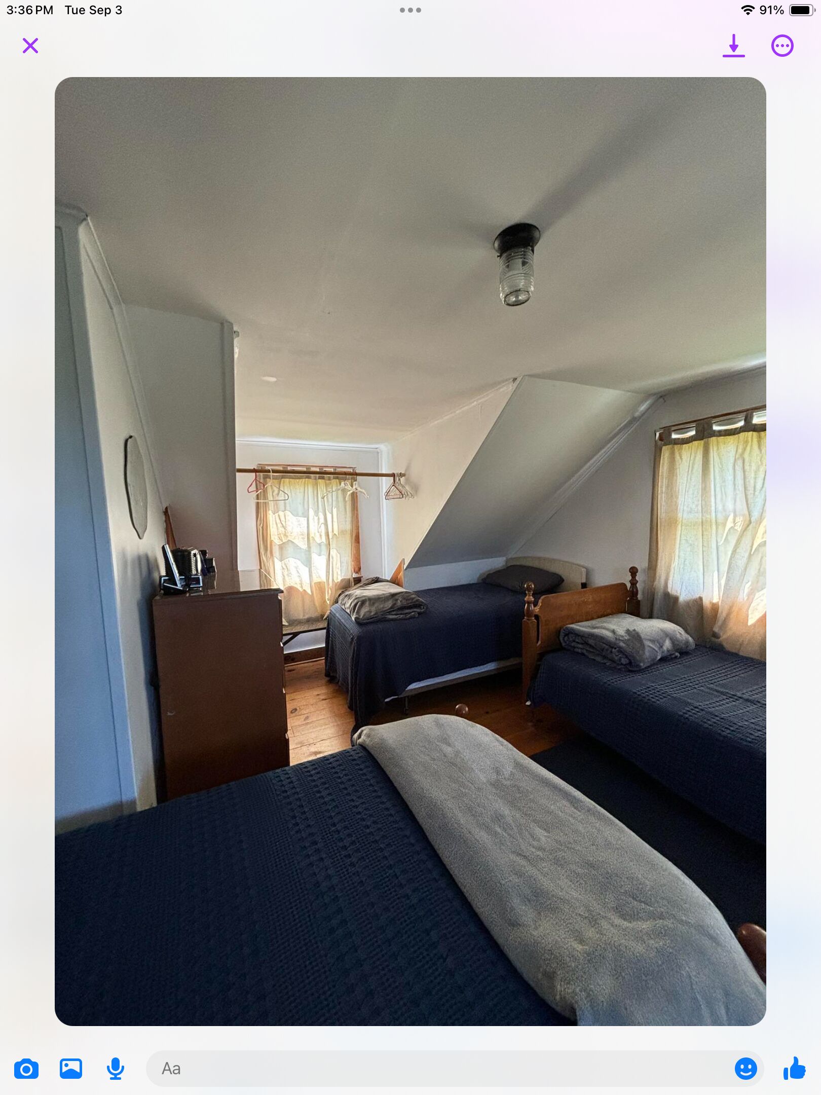Une chambre avec deux lits, un bureau et une fenêtre avec des rideaux.