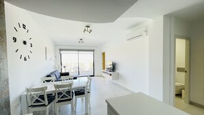 A modern living room with a dining area, a large wall clock, and a view to the outside. - 3090 RESIDENCIAL SABRINA (Orihuela Costa)