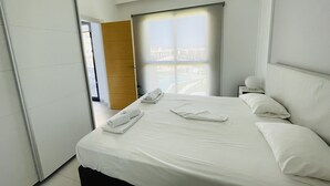 A modern hotel room with a large bed, a nightstand, a window with a view, and a wooden door. - 3090 RESIDENCIAL SABRINA (Orihuela Costa)