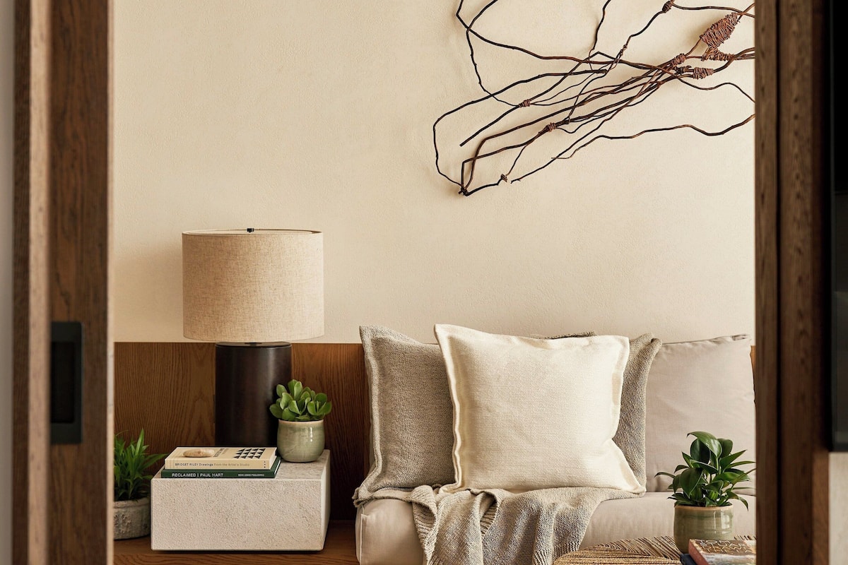 A cozy living room with a sofa, a round coffee table, a lamp, and decorative wall art.