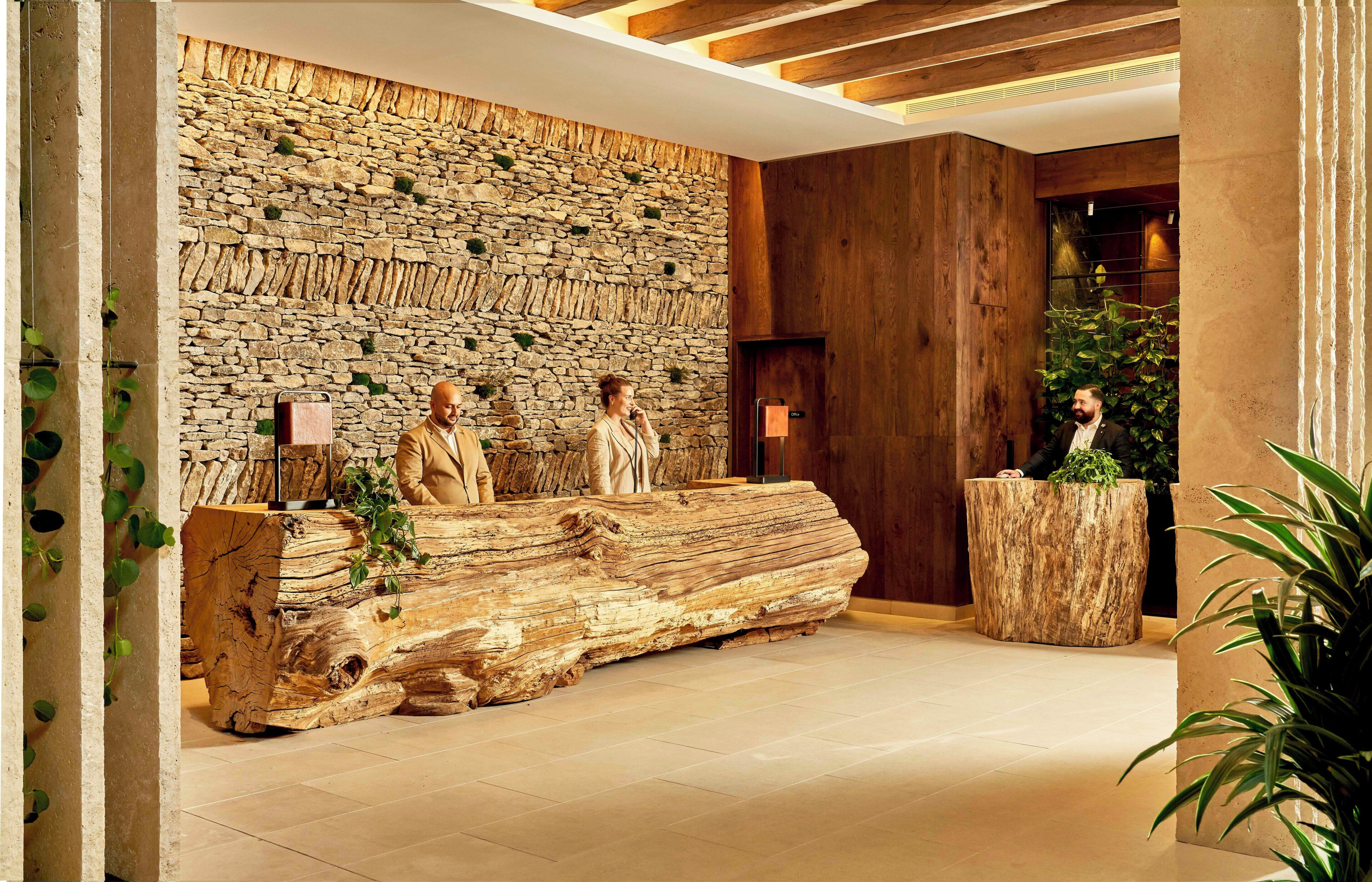 A reception area with a stone wall, wooden paneling, and a large log bench.