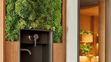 A modern bathroom with a built-in sink, wooden cabinetry, and a moss wall.