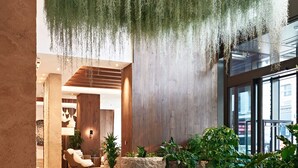 A spacious lobby with hanging greenery, stone planters, and a modern interior design. - 1 Hotel Mayfair (London)
