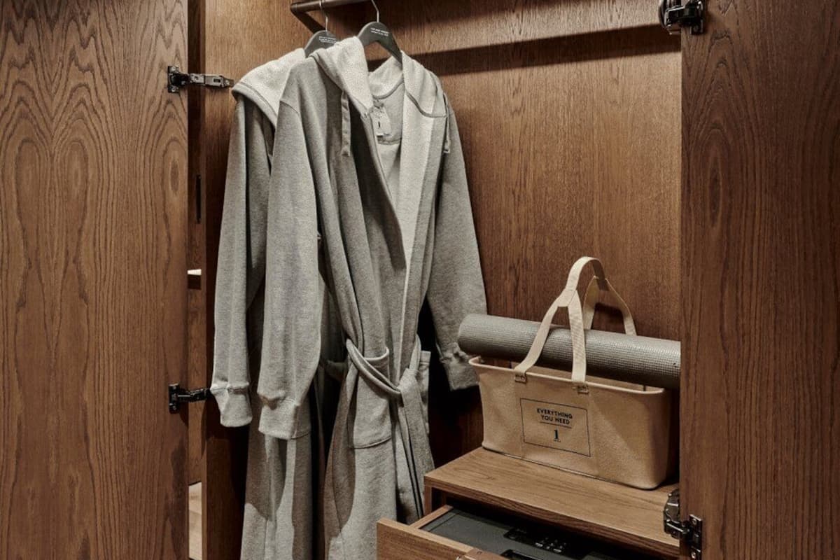A wooden wardrobe with a robe hanging, a yoga mat, and a storage box labeled 'EVERYTHING YOU NEED'.