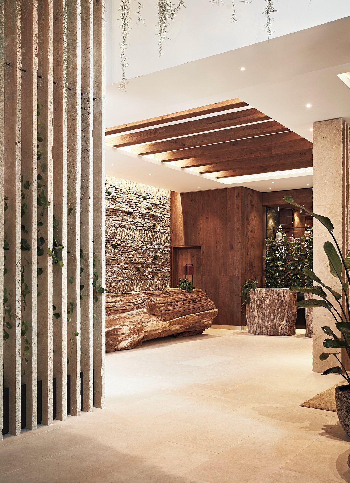 Un interior moderno con pared de piedra, vigas de madera y plantas en macetas.