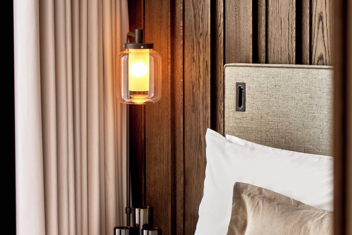 A neatly made bed with a white headboard, a beige pillow, and a textured white throw blanket.