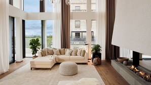 A modern living room with a sectional sofa, ottoman, and a fireplace. - 1 Hotel Mayfair (London)