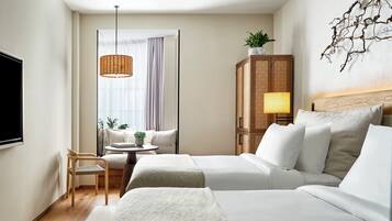 Een hotelkamer met twee bedden, een televisie, een rieten lamp, een houten kast en een plant.