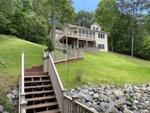 A two-story house with a covered porch and a stone retaining wall.