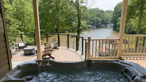 A hot tub on a deck with a view of a river and forest.