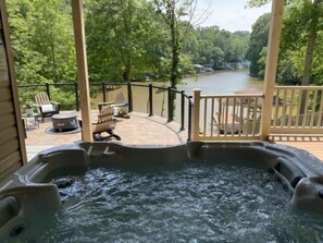 Ein Whirlpool auf einer Terrasse mit Blick auf einen Fluss und Wald.