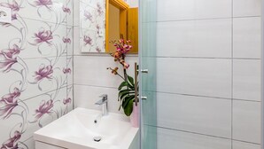 A bathroom with a white sink, a mirror, and floral wallpaper. - Apartments and Room Frane - Double Room (Dubrovnik)