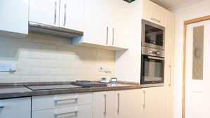 A kitchen with white cabinets, a microwave, and an oven. - 4 Bedroom-southampton-sleeps 6- Garden (Southampton)