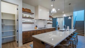 A modern kitchen with a central island, bar stools, pendant lighting, and built-in shelves. - Arcadia 64 | Private Hot Tub * Views * Arcade * Pool Table (Santa Clara)