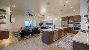 A modern kitchen with a central island, built-in appliances, pendant lighting, and a dining area with a view. - Arcadia 64 | Private Hot Tub * Views * Arcade * Pool Table (Santa Clara)