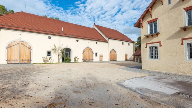 A building with a red-tiled roof, large wooden doors, and arched windows. - Spacious Dual Guesthouse (Haunsheim)