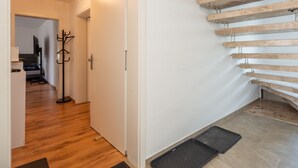A modern interior with a wooden staircase, a coat rack, and a hallway leading to another room. - Spacious Dual Guesthouse (Haunsheim)