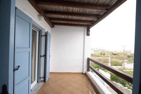 Ein Balkon mit Holzboden, einer weißen Wand und Blick auf eine weite Landschaft.