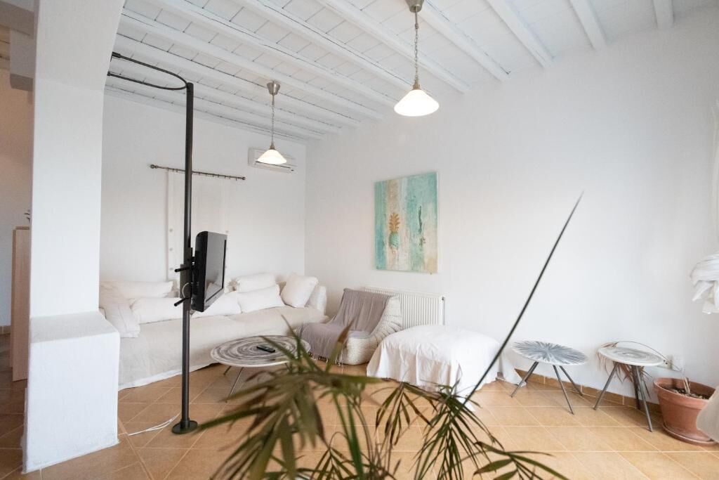A modern living room with a white sofa, a coffee table, a floor lamp, a painting on the wall, and a potted plant.
