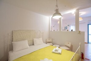 Ein Schlafzimmer mit einem Bett, einem Nachttisch, einem Sessel und einem Spiegel.