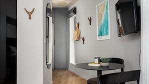 A modern kitchen with a round dining table, wooden flooring, and a view of the adjacent living area. - Charming Apartment with Mountain Views (Cape Town)