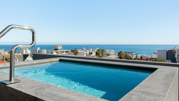 A swimming pool with a view of the ocean and buildings. - Charming Apartment with Mountain Views (Cape Town)