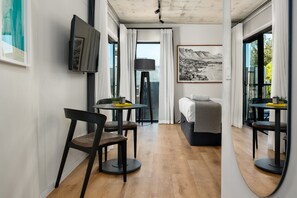 A modern hotel room with a bed, a desk, a chair, a TV, and a large window.