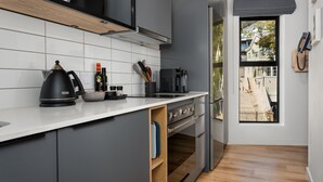 A modern kitchen with a built-in oven, a coffee maker, and a kettle on the counter. - Charming Apartment with Mountain Views (Cape Town)
