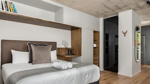 A modern bedroom with a large bed, a bedside table, a mirror, and built-in shelving. - Charming Apartment with Mountain Views (Cape Town)