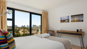 Een hotelkamer met een groot bed, een bureau en uitzicht op de stad.