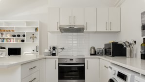 Een moderne keuken met witte kasten, een oven, een magnetron en een wasmachine.