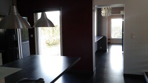 Une cuisine moderne avec un plan de travail foncé, un luminaire suspendu et une vue sur un jardin par une fenêtre.