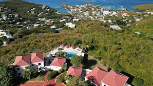 An aerial view of a coastal area with residential buildings, a swimming pool, and a view of the sea and islands in the distance. - 2 bedroom, 2.5 bath with pool access & ocean view (Cruz Bay)