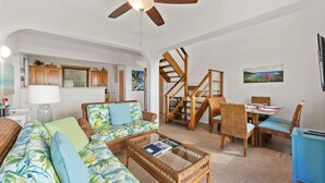 A living room with a sofa, coffee table, and dining area with chairs and a table. - 2 bedroom, 2.5 bath with pool access & ocean view (Cruz Bay)