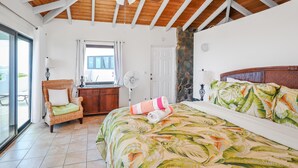 A bedroom with a bed, a chair, a desk, a fan, and a view of the outdoors. - 2 Bedroom Villa with Pool & Panoramic Views (Cruz Bay)