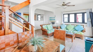 A living room with wicker furniture, a wooden staircase, and a ceiling fan. - 2 Bedroom Villa with Pool & Panoramic Views (Cruz Bay)