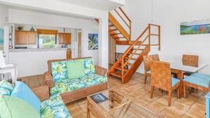 A living room with a sofa, chairs, a dining table, and a staircase. - 2 Bedroom Oceanview Villa w/ Pool & Courtyard – St. John (Cruz Bay)