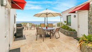 A patio with a table and chairs, an umbrella, and a view of the ocean. - 2 Bedroom Oceanview Villa w/ Pool & Courtyard – St. John (Cruz Bay)