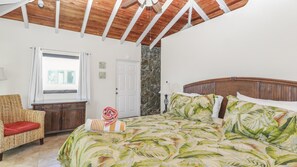 A bedroom with a bed, a wooden ceiling, a window, a door, and a chair.